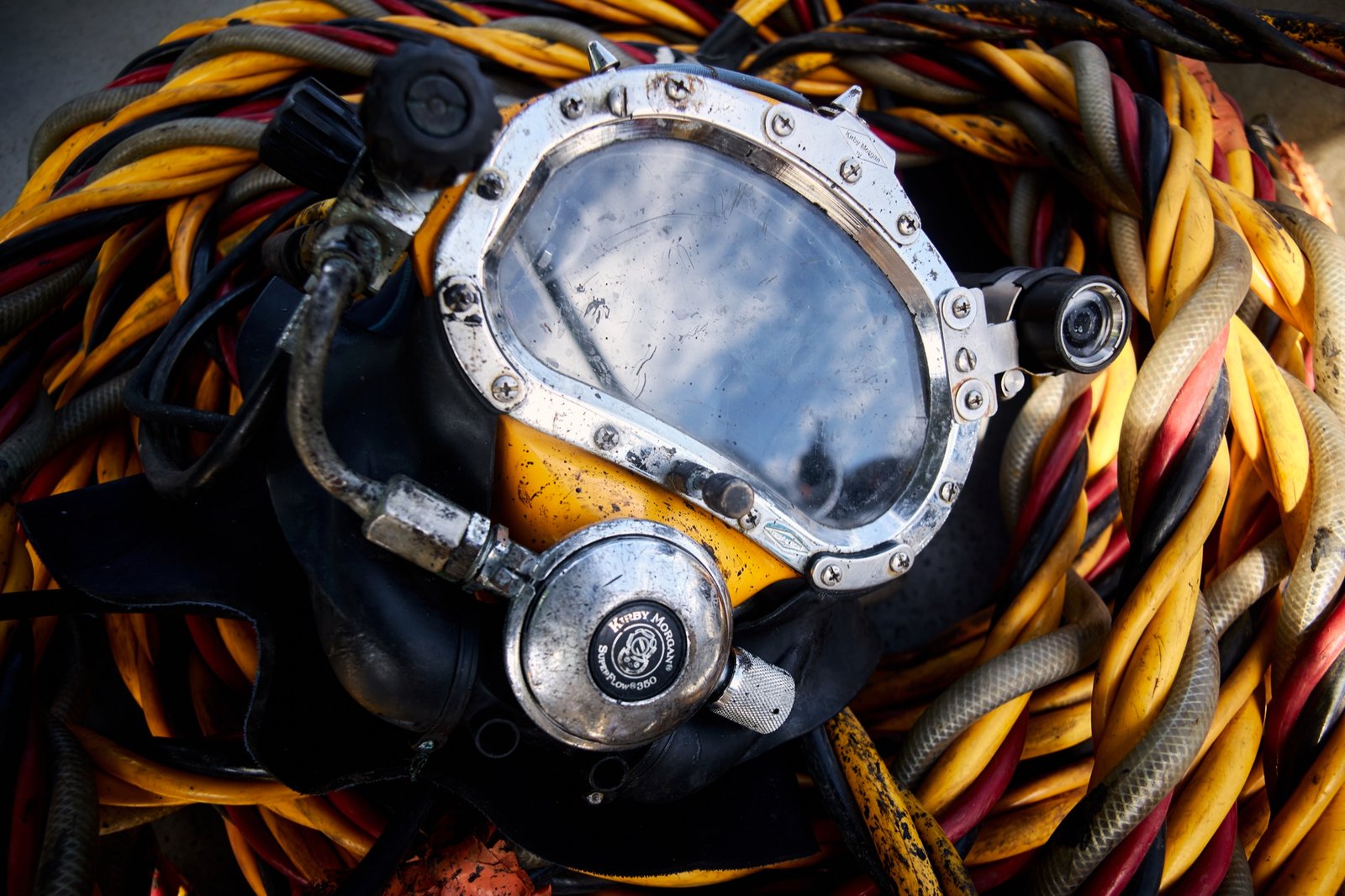 Vintage commercial diving helmet on coiled umbilical hoses