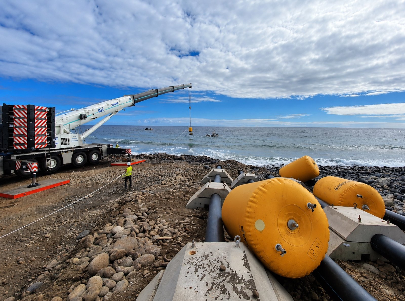 Mobile crane loading marine equipment with buoys on rocky coast